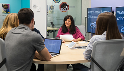 Students around table with Communication Studies department chair Leslie DeChurch discussing the NASA astronauts' team dynamics work