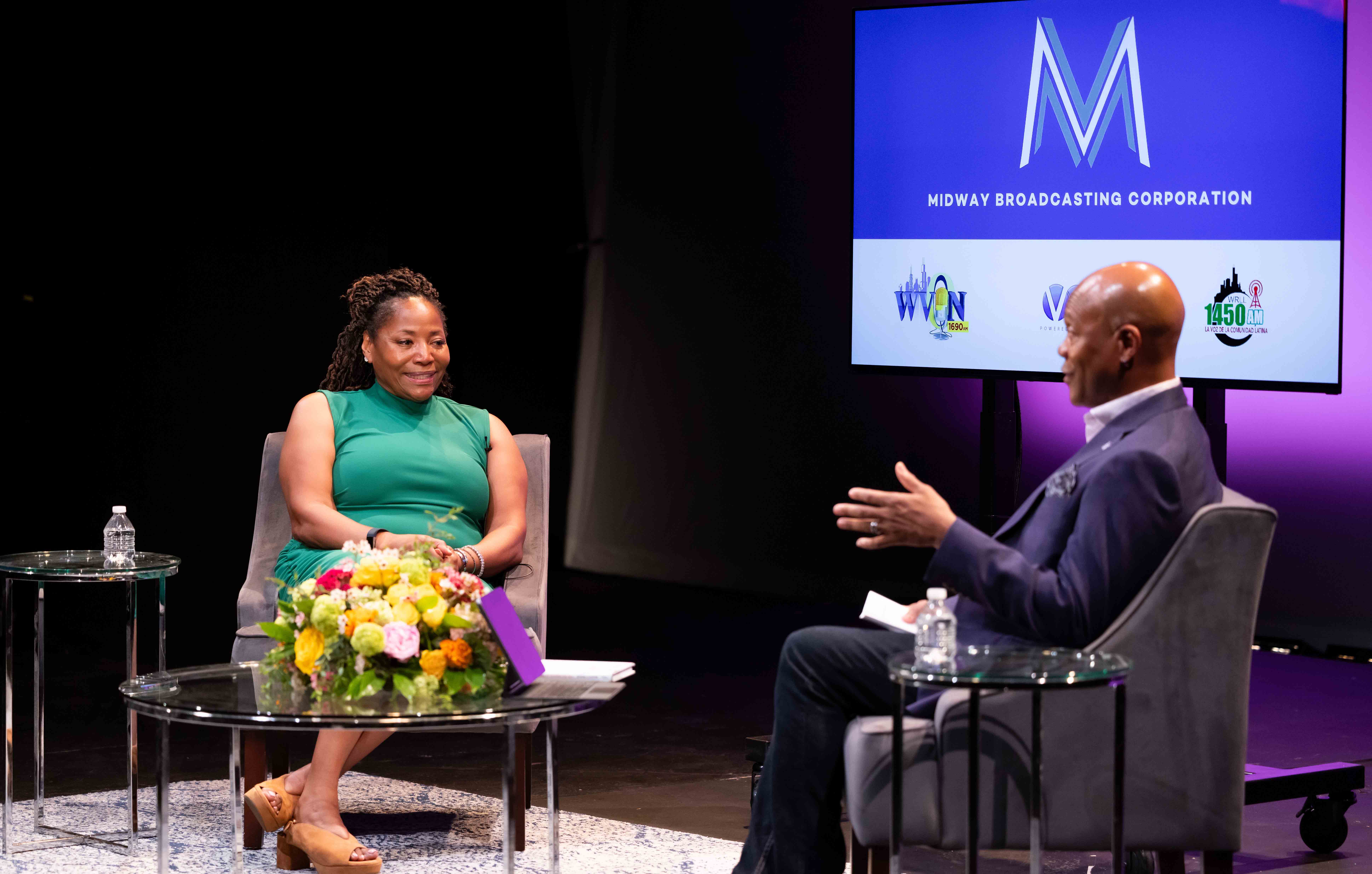 Melody Spann Cooper in green dress talks to E. Patrick Johnson